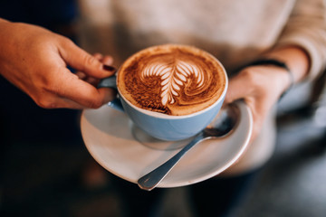 A person holding a cup of coffee with a drawing 