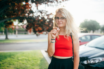 Young blonde girl with sunglasses holding a candy pill