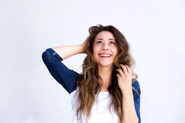 Laughing young woman with hand in hair looking up