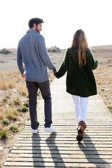 Beautiful young couple in love walking in a cold winter on the beach.