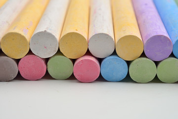 Pieces of chalks in a variety of colors arranged in lines on a white background. Back to school,education, arts, creative. Image with room for text