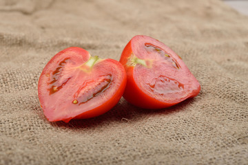 Fresh red tomato cut in half on jute canvas. Healthy nutrition