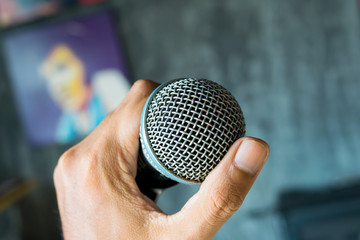 close up hand holding microphone on music hall