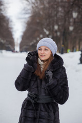 young beautiful girl in a fur coat on a walk in a winter park