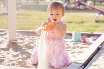 Little girl playing with sand in a sandbox