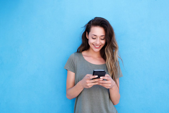 young smiling woman using mobile phone against blue background