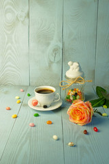 Easter composition. Rose, a jar with Easter Bunny, a cup with coffee, candy.