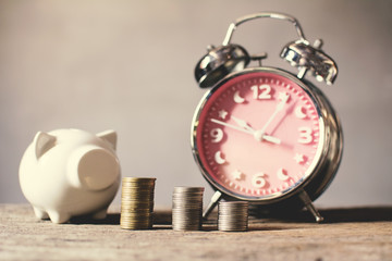 coin with alarm clock piggy bank on old wood  background, a color of vintage tone concept time to save money