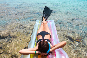 Woman resting on pool raft in flappers and snorkel
