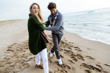 Happy young couple enjoying the day in a cold winter on the beach.