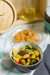 Asian food with vegetables and shrimps. Sesame oil, bowls, bamboo steamer.