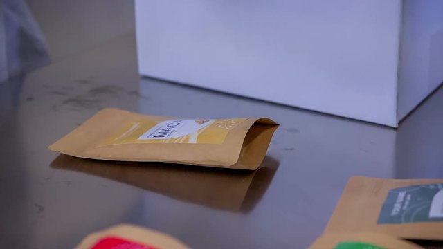 A pharmaceutical factory worker is putting small bags with goji berries, maca chlorella and chia seeds into a big box.
