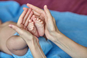 Mother's hands carefully holding baby's feet, selective focus