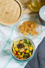 Asian food with vegetables and shrimps. Sesame oil, bowls, bamboo steamer.