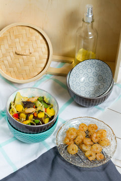 Asian food with vegetables and shrimps. Sesame oil, bowls, bamboo steamer.