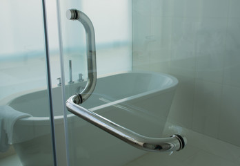 Soft focused picture of stainless steel handle with glass door in luxury bathroom