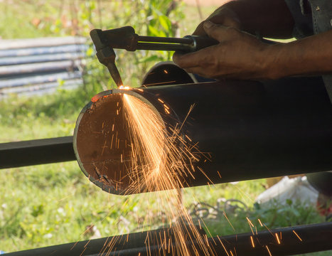 Soft focused picture of  Worker man is cutting round steel pipe by gas cutter
