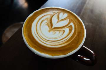 Coffee cup with latte art on the wood table
