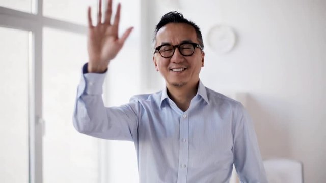happy asian businessman waving hand at office