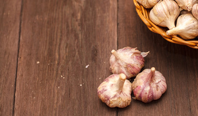 heads of garlic in a wicker basket on a wooden background