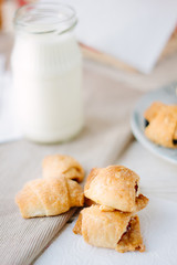Home made croussants over fabric material with milk in bottle.