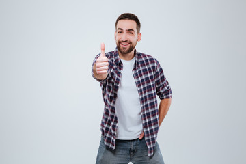 Fototapeta premium Smiling Bearded man in shirt showing thumb up at camera