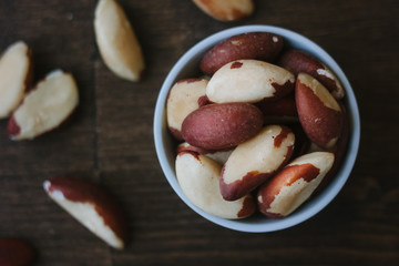 Brazil nuts on white ceramic bowl over the wooden table