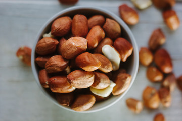 Dry peanuts in white bowl over the white table