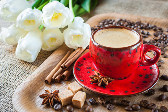 cup of coffee on wooden background decorated with spices and flowers