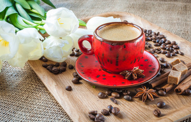 cup of coffee on wooden background decorated with spices and flowers