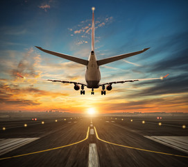 Fototapeta na wymiar Airplane landing to airport runway in sunset light