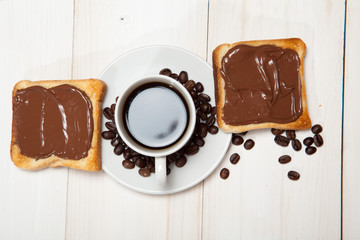 cup of coffee and toast with chocolate on a white wooden table