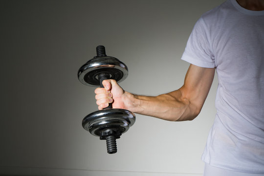Young Man in a white shirt doing biceps exercises.