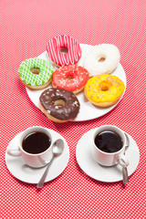 Two cups with coffee and donuts on a red background