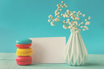 Blank paper card with cup of tea andvase in flower and macaroons for woman day