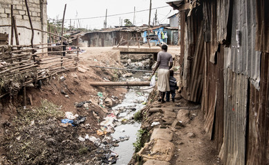 People walking along an open sewer in a slum in Africa