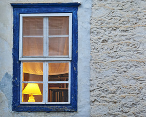 Greece, illuminated house interior through blue frame window