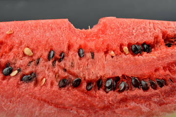 Close up of fresh watermelon with bunch of seeds with a bite isolated on black background