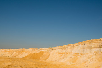 Fototapeta na wymiar cliff of the yellow orange brown sand soil clay under the bright sunny day with deep blue sky