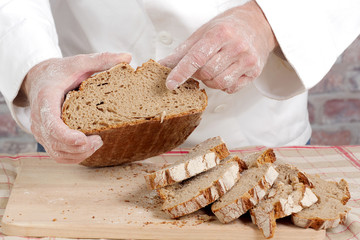 Baker hands with fresh bread on wood table