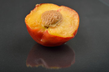 Close up image of a peach cut in half on black background. Section through the middle of the fruit, kernel. Selective focus