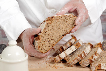 Baker hands with fresh bread on wood table