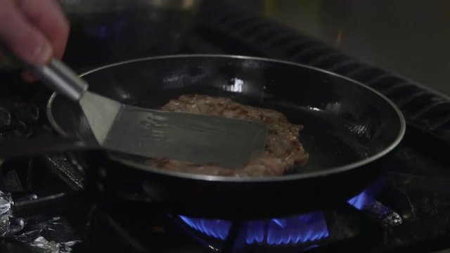 Chef turning a steak in a pan