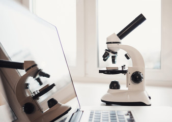 Laptop computer and microscope on a table in laboratory, science or education research concept
