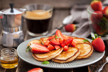 Homemade delicious pancakes served with fresh strawberries and honey