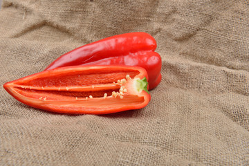 Half of red pepper lying on on sackcloth background. Concept of healthy food, bio from countryside