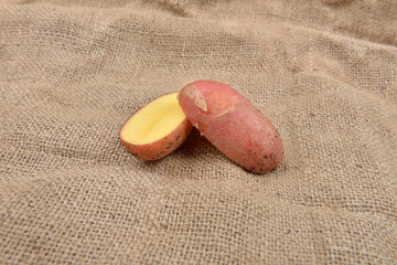 New fresh red potatoes cute in two on jute background. Concept of healthy food, bio from countryside