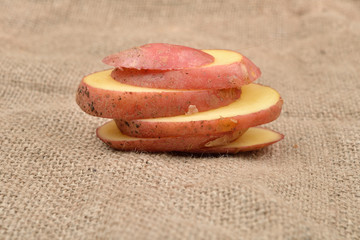 New fresh red potatoes cute in slices on jute background. Concept of healthy food, bio from countryside