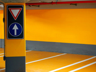 Yellow subterranean parking with street signs on a column