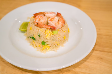 Traditional Thai food : Fried jasmin rice with shrimps and fried egg in white dish put on the wooden table with copy space.
